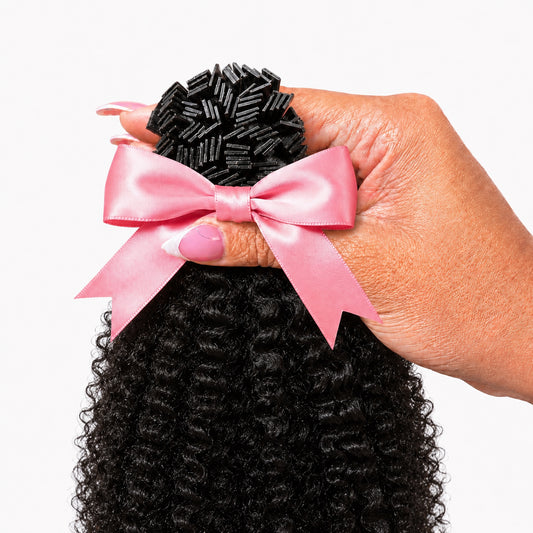 1B Looser than 4C K-Tip extensions 100g pack held in hand with pink satin bow — Natural Coily Collection by TT Does It All